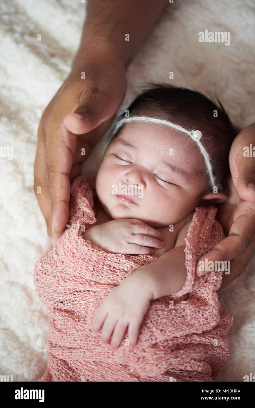 African american take care of white newborn baby. Father hands hold baby girl Stock Photo