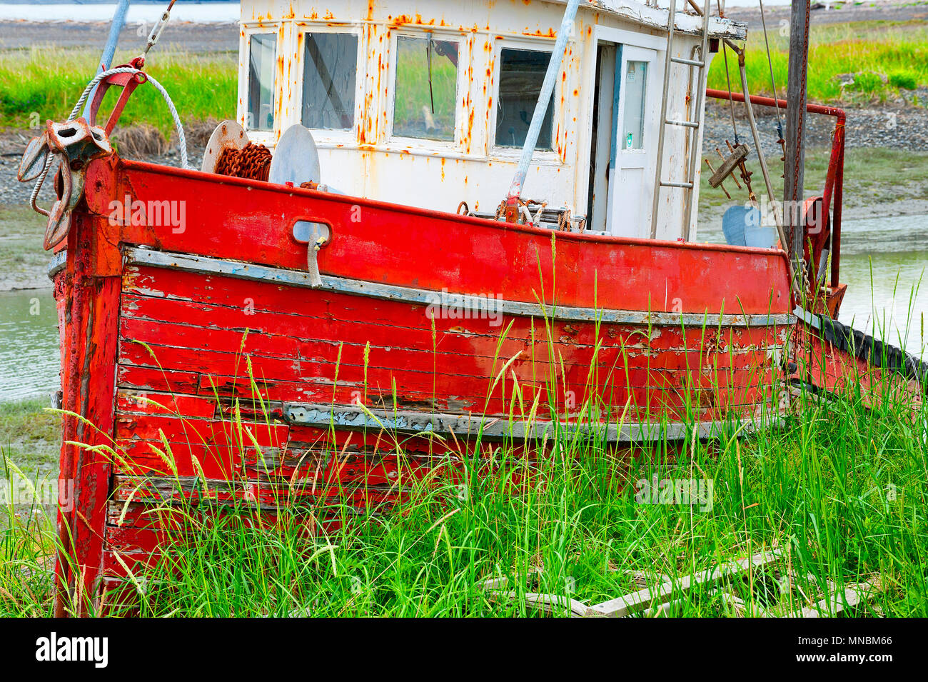 Decaying abandoned boat in a grassy field seen from walking path along the shores of Kachemak Bay in Homer Alaska. Stock Photo