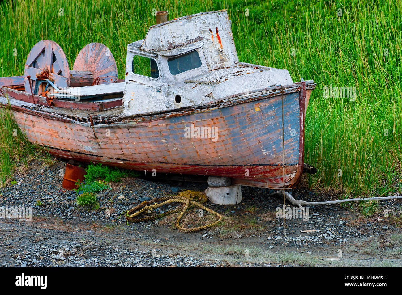 Decaying abandoned boat in a grassy field seen from walking path along the shores of Kachemak Bay in Homer Alaska. Stock Photo