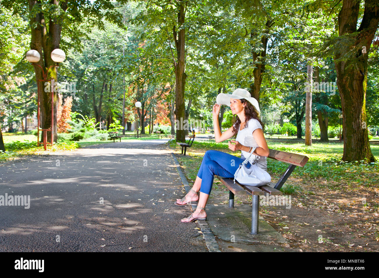 Beautiful young woman sitting on the bench in park in Mataruska banja, Serbia. Stock Photo