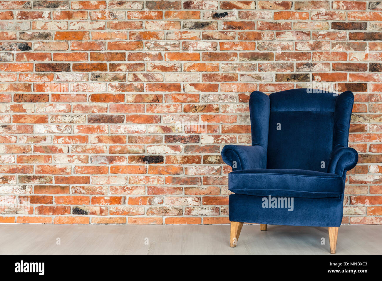 Picture of Industrial style brick wall and blue upholstered armchair Stock Photo ...