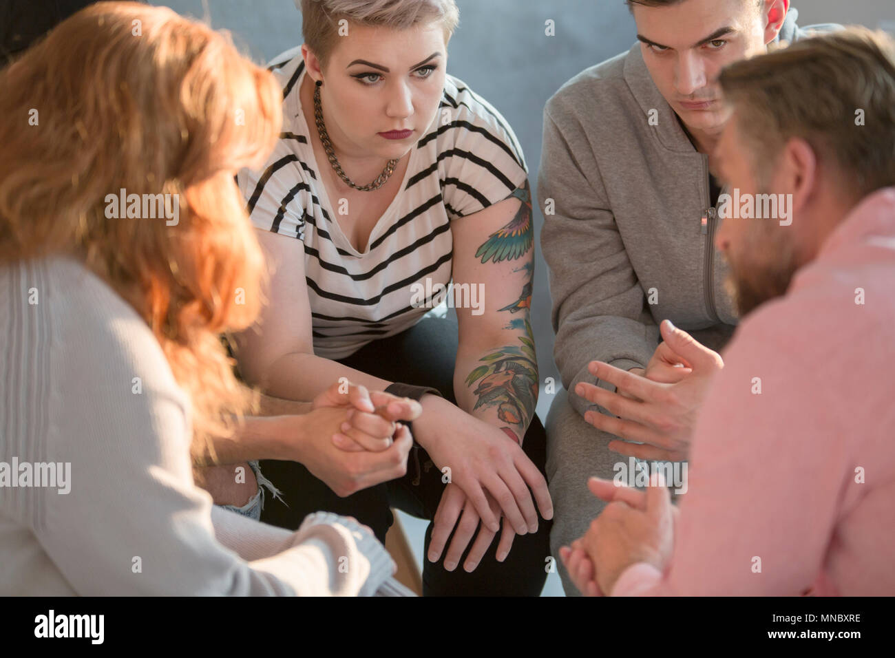 People sitting in circle, listening to their psychotherapist Stock Photo
