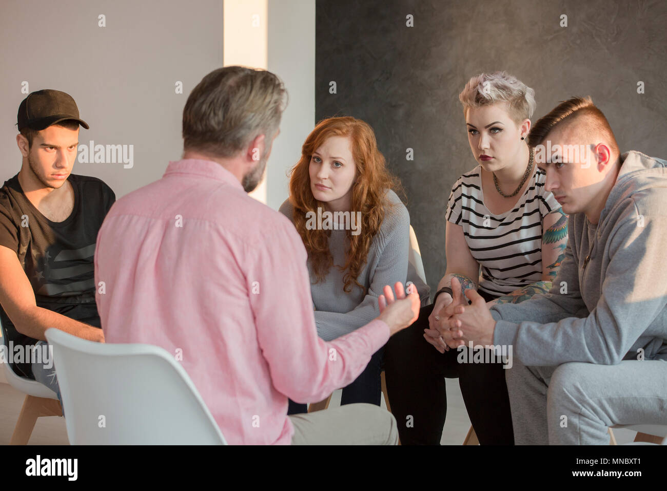 Addiction counselor talking to group of his teenage patients Stock Photo