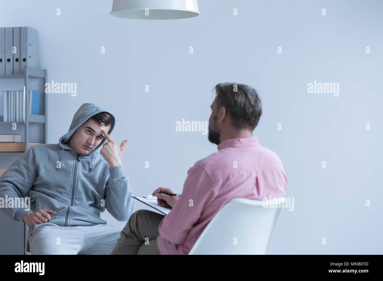 Rebellious teenage boy talking with his psychologist Stock Photo