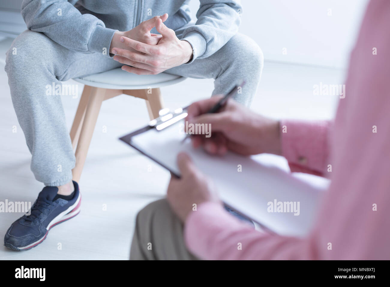 Psychologist taking notes during meeting with his teenage patient Stock Photo