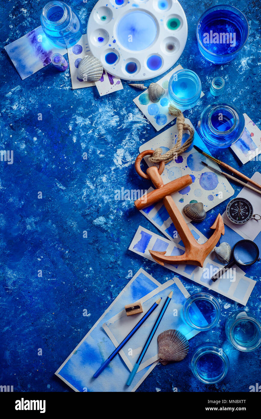Travel flat lay with wooden anchor, fantasy map, watercolor sketches, seashells and compass on a navy blue background with copy space. Creative artist Stock Photo