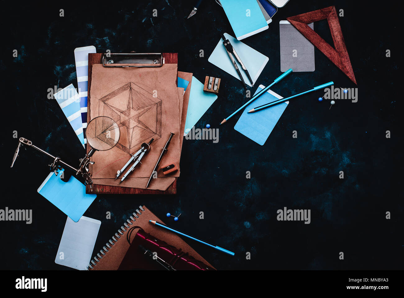 Draftsman or designer workplace with craft paper, sketches, compasses, rulers, clipboards and pencils on a dark stone background. Top view with copy s Stock Photo