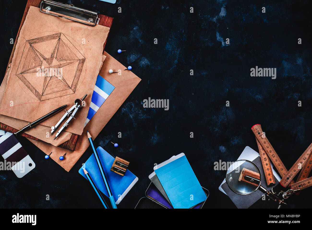 Header with draftsman or designer workplace with craft paper, sketches, compasses, rulers, clipboards and pencils on a dark stone background. Top view Stock Photo