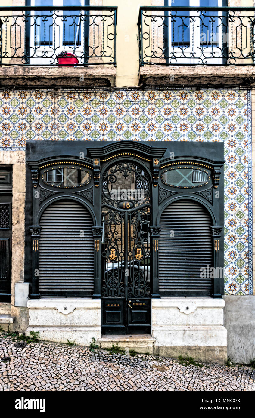 Facade of townhouse in Martim Moniz with ornate black door with gold decoration, surrounded by ceramic tiled wall Stock Photo