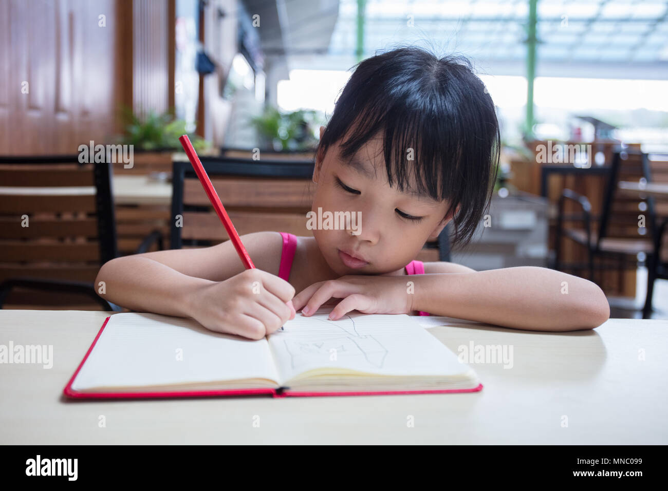 Asian Chinese Little Girl Doing Homework At Outdoor Cafe Stock