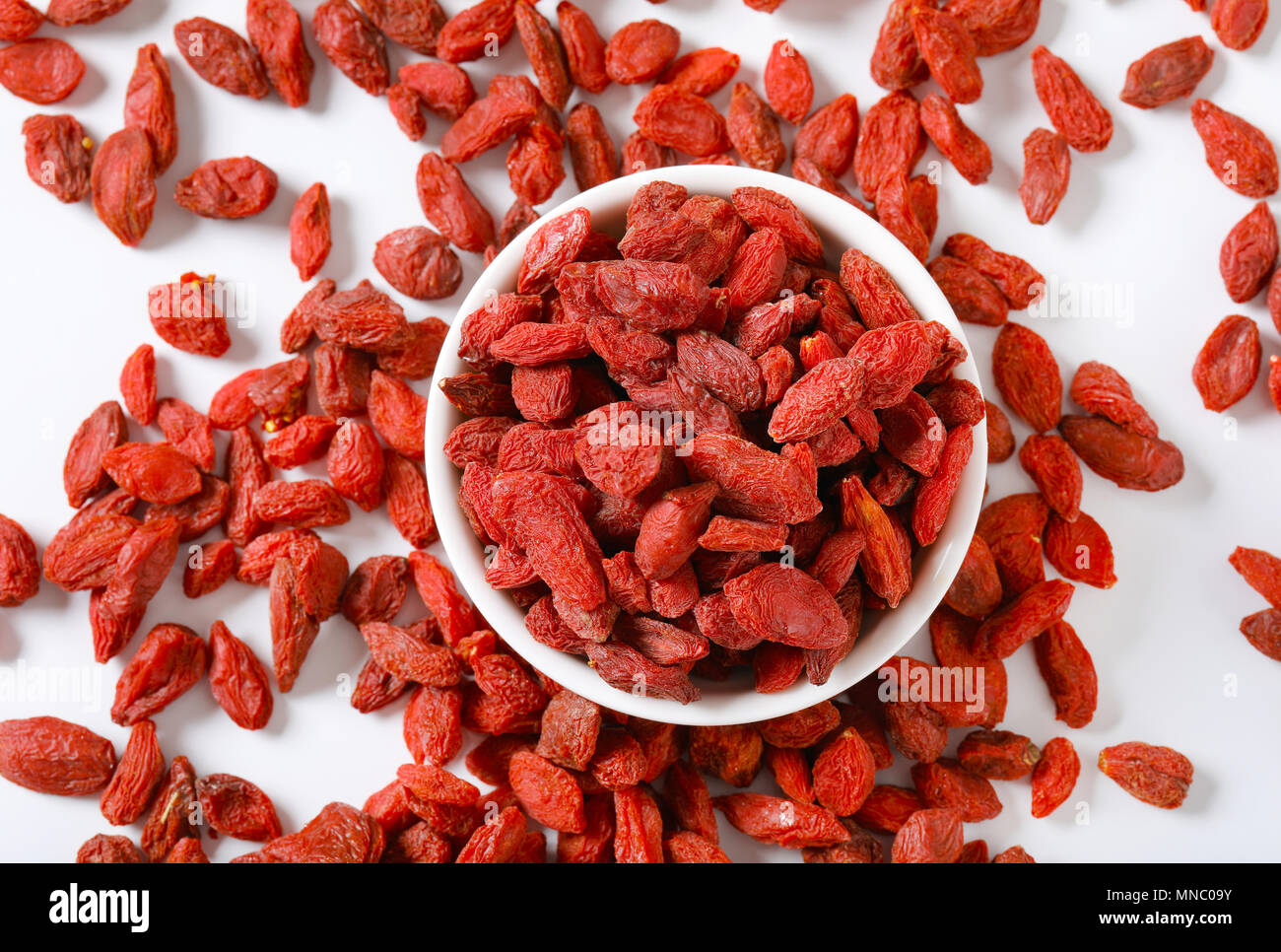 bowl and pile of healthy goji berries on white background Stock Photo