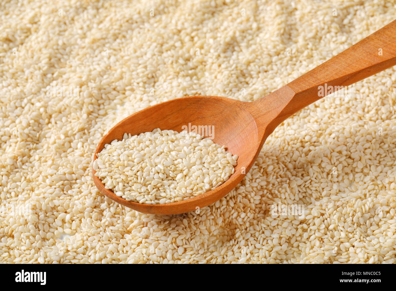 spoon of healthy sesame seeds on sesame seeds background Stock Photo