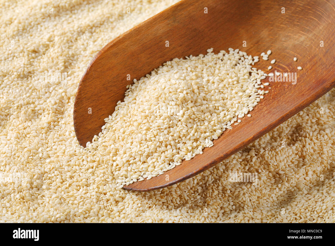 scoop of healthy sesame seeds on sesame seeds background Stock Photo