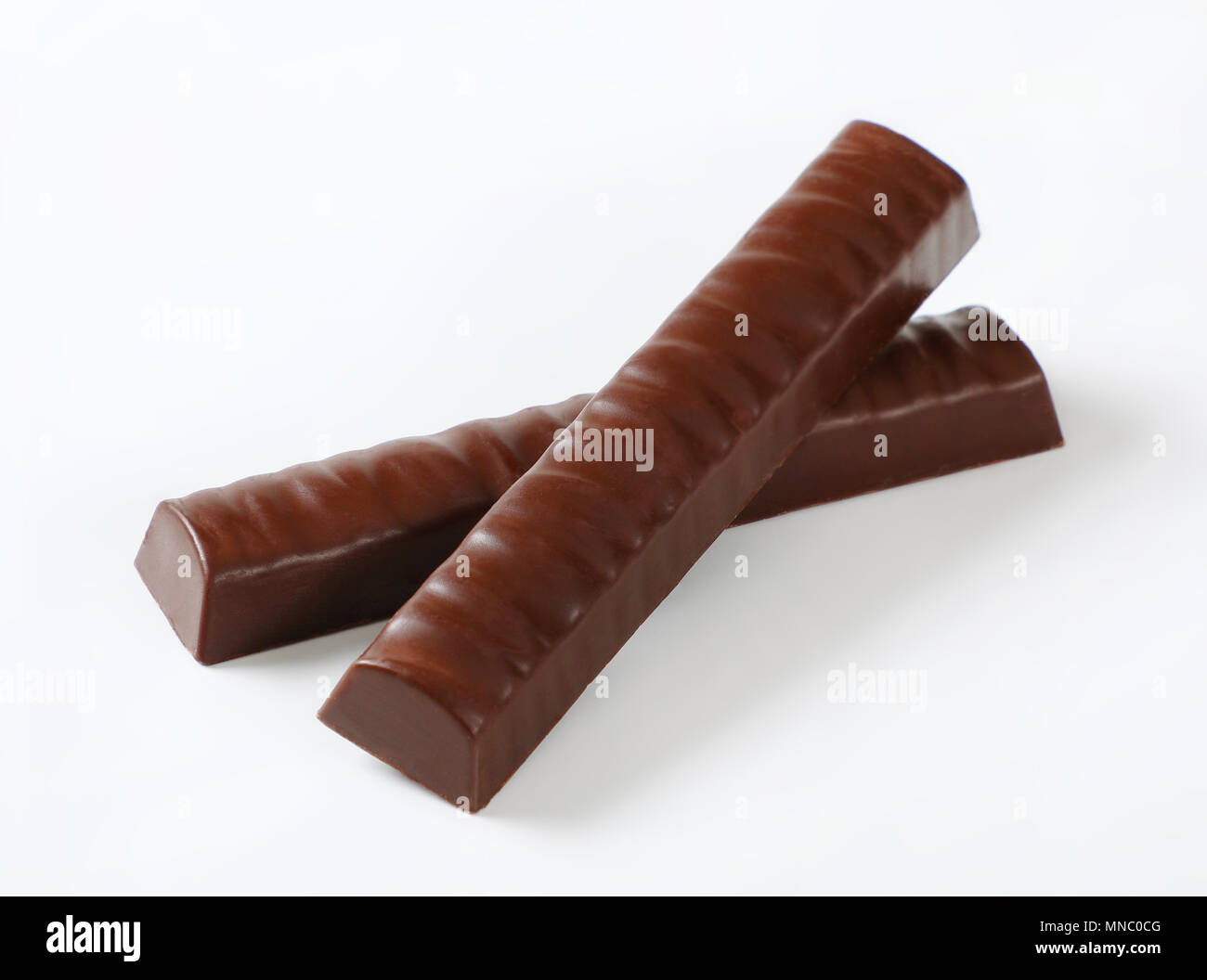 two unwrapped chocolate sticks with filling on white background Stock Photo