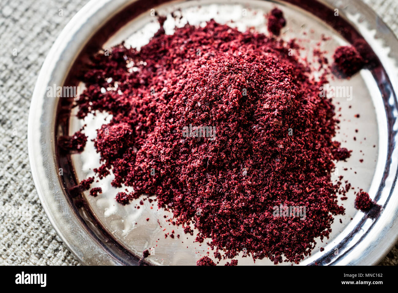 Dried Sumac, sumah or sumak on silver plate (arabic cuisine) Organic