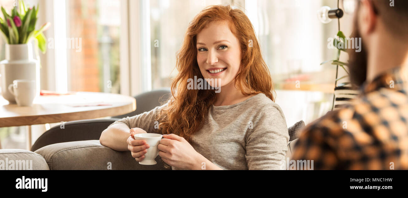 Panorama of smiling woman drinking tea and looking at her husband Stock Photo