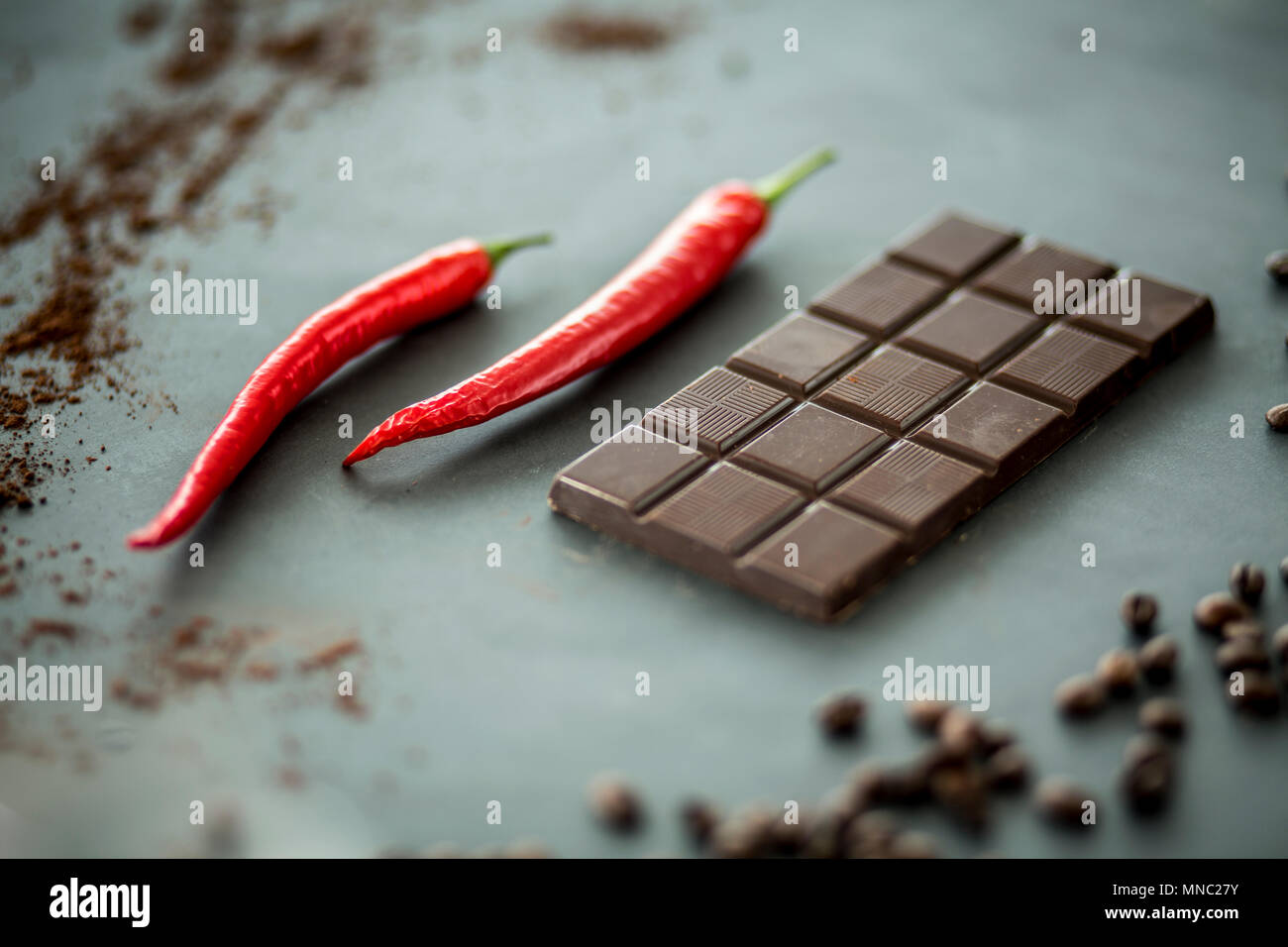 Closeup of hot, red peppers next to a bar of dark chocolate. Mixing