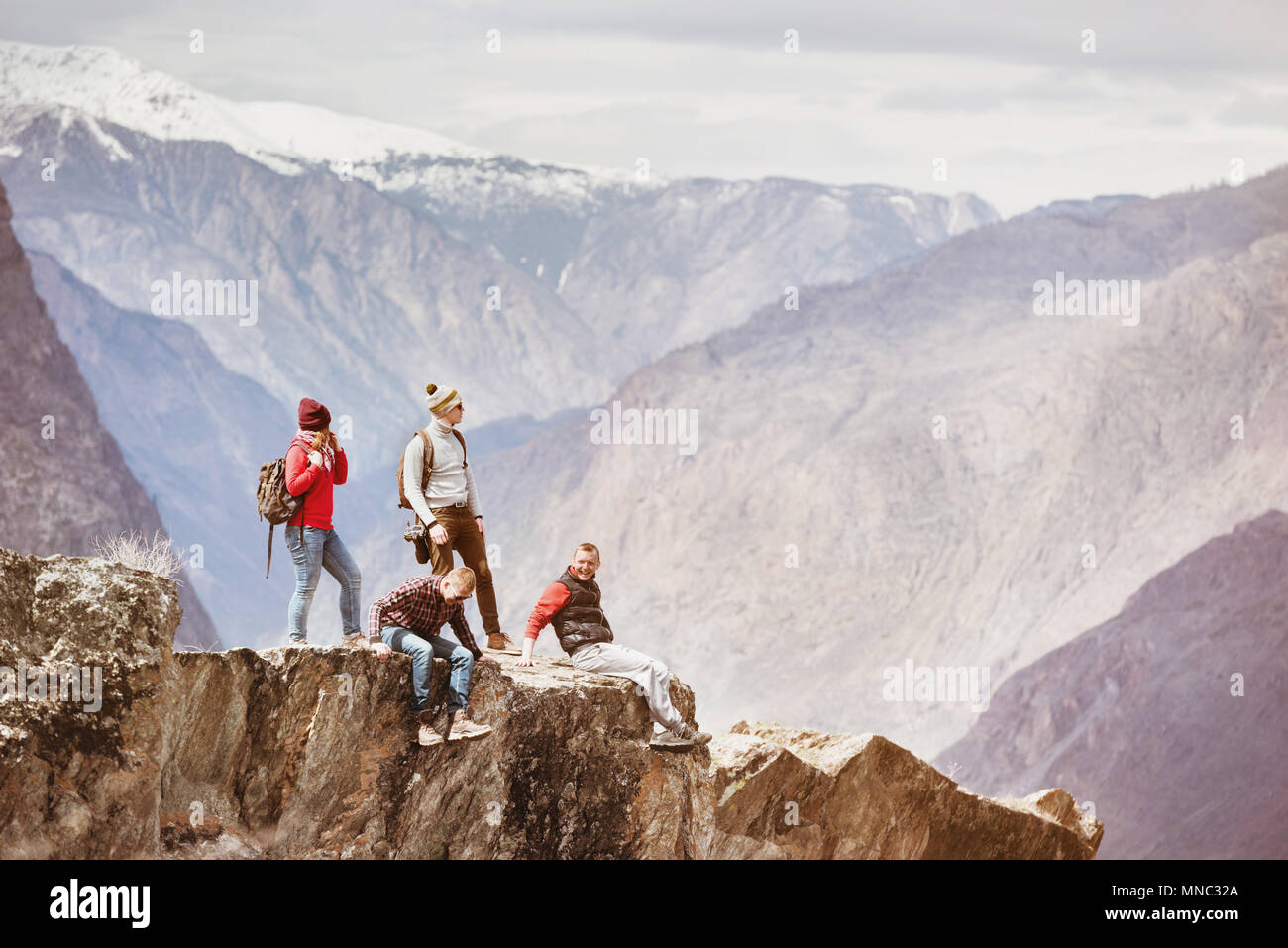 Four active friends on cliff mountain top Stock Photo