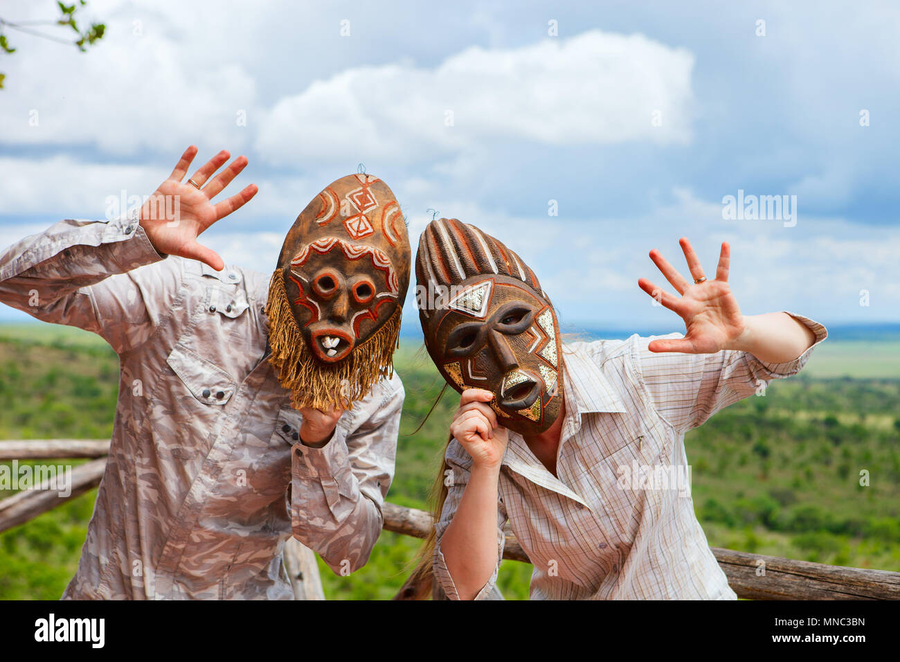 African vacation. Happy couple in african masks at balcony in safari lodge. Stock Photo