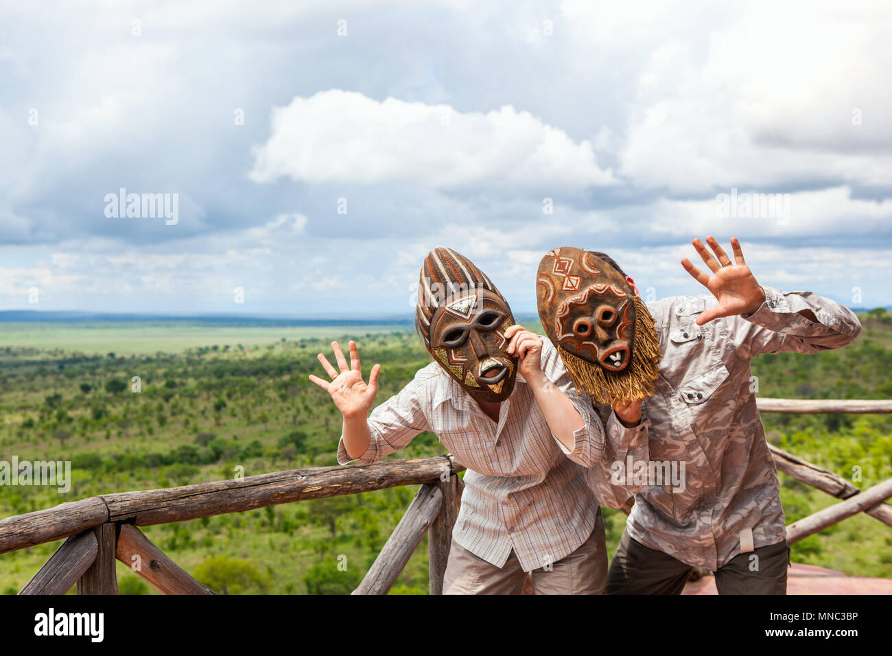 Couple in African masks standing at balcony with view to savanna Stock Photo