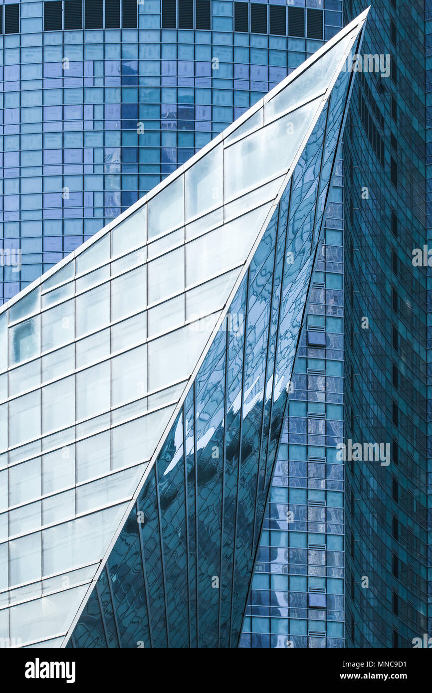 Modern architecture, abstract vertical fragment, sharp corner made of glass and steel with reflections of blue sky Stock Photo