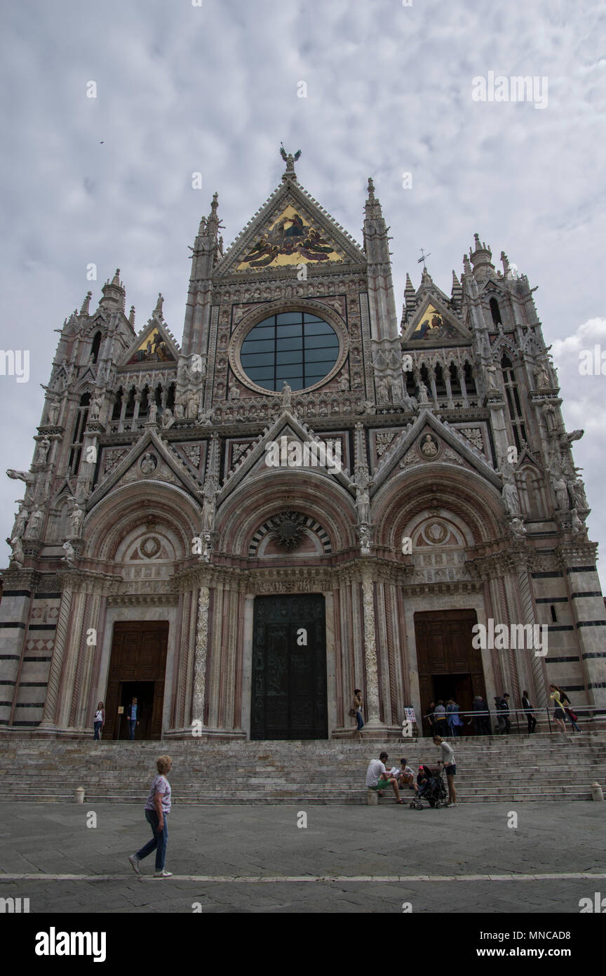 Imposing fascade of the dome duomo in the beautiful Italian city of Siena on a sunny day with white clouds with gold ornamentation Stock Photo