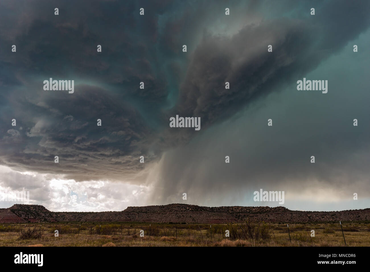 A supercell thunderstorm with dark clouds and a green hail core approaching Tucumcari, New Mexico, USA. Stock Photo