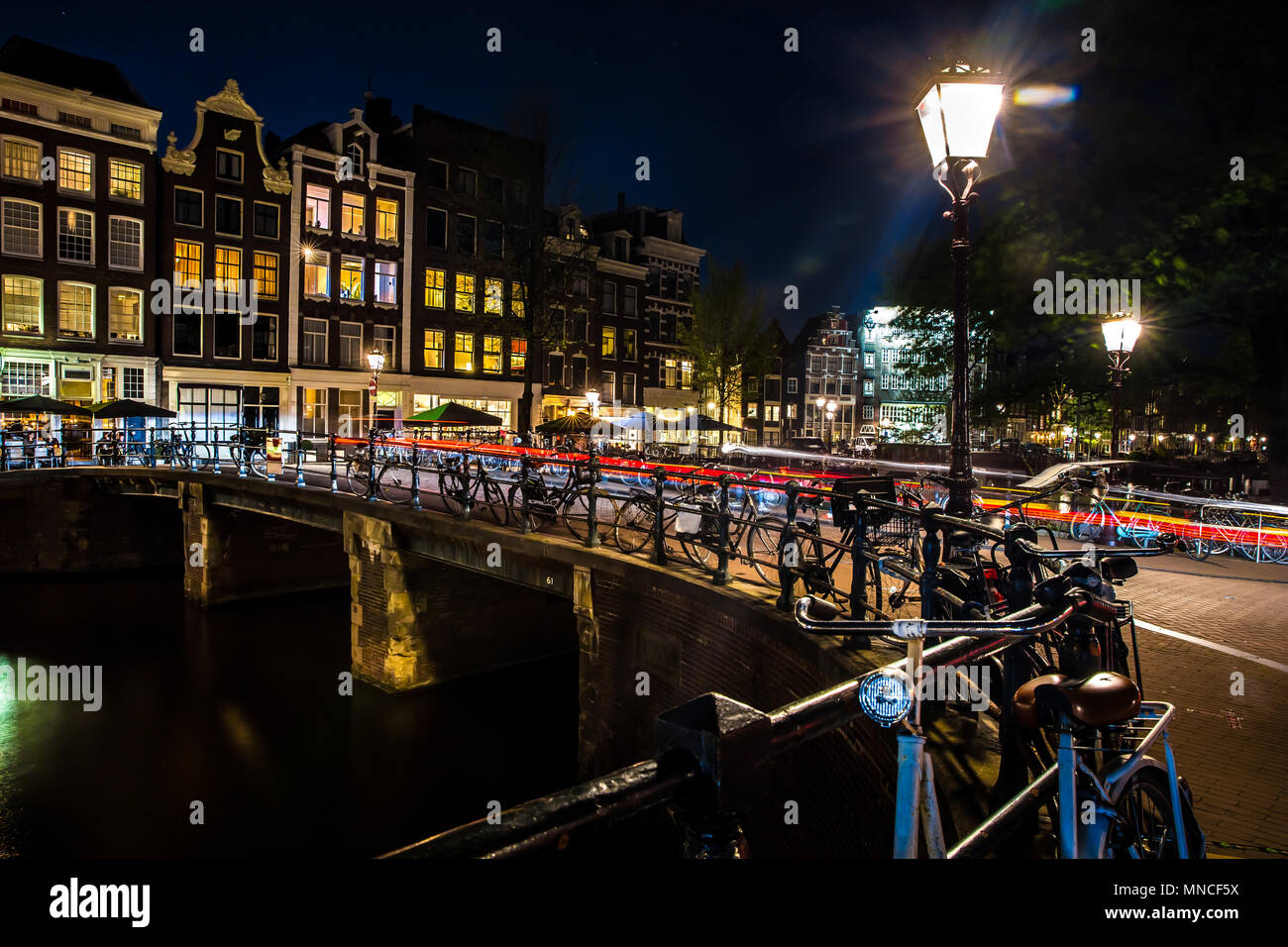 Night view with bridge, bicycles and water reflection in Amsterdam city, Netherlands Stock Photo