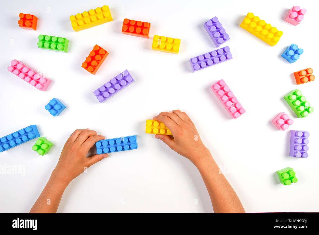 Kid hands play with colorful plastic construction blocks on white ...