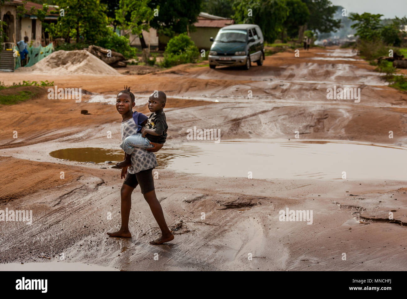 Yongoro, Sierra Leone - May 31, 2013: West Africa, the road after a storm with the holes full of water leading to Longi from Yongoro in front of the c Stock Photo