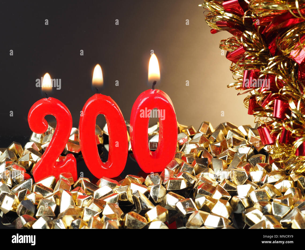 Birthday-anniversary candle showing Nr. 200 Lit red candle good for an anniversary or birthday background. Stock Photo