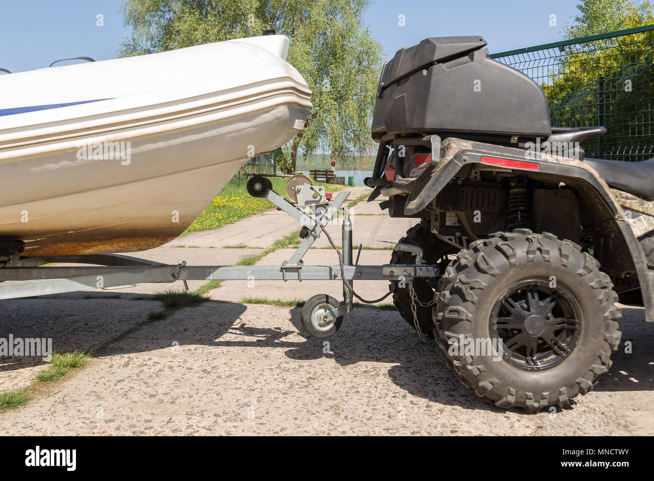 Transportation of inflatable boat on trailer. ATV quadbike moves ship ...