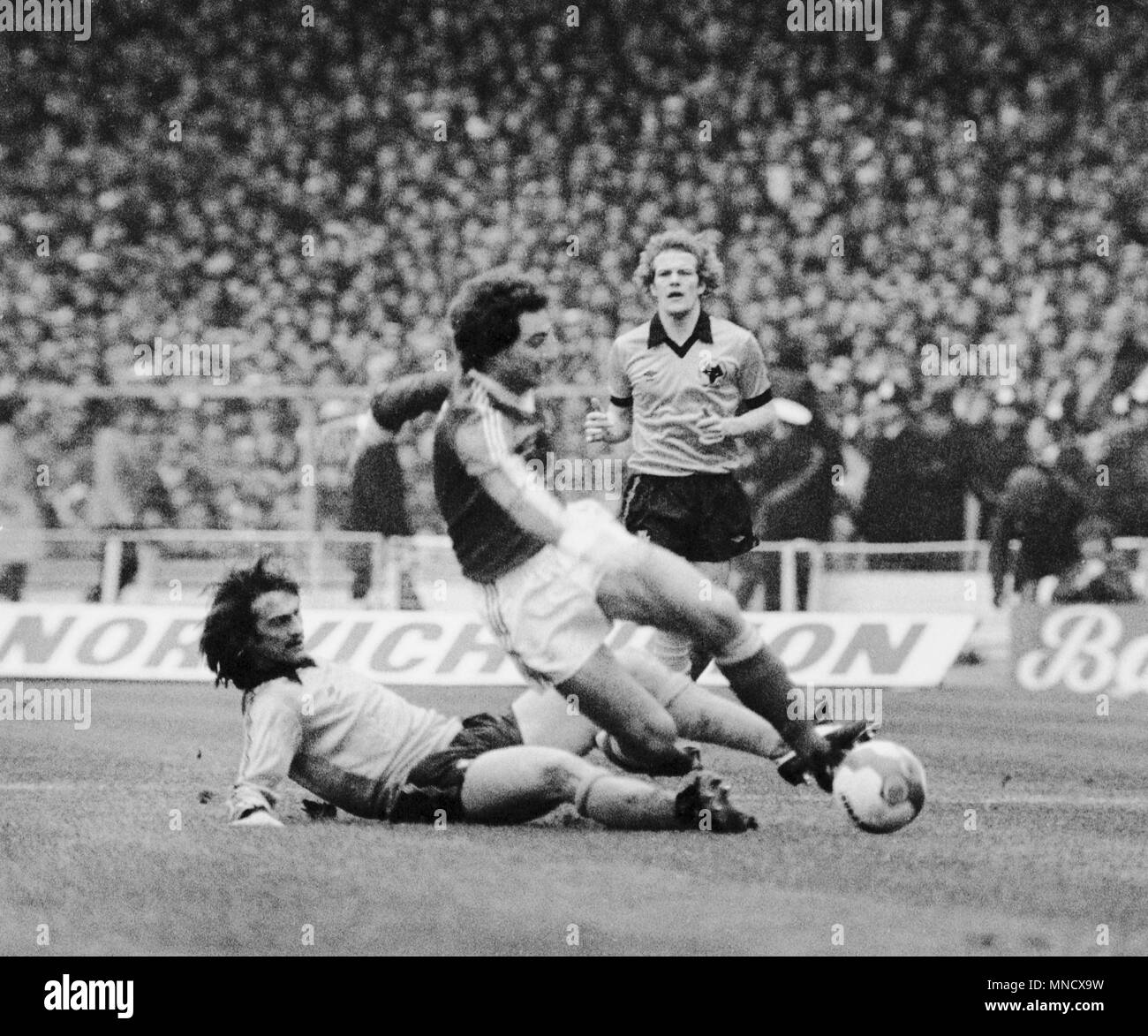 Martin O'Neill (c), in possession for Nottingham Forest, evades a sliding tackle from Kenny Hibbitt, of Wolverhampton Wanderers, as team-mate Andy Gray looks on during the Football League Cup final at Wembley. Stock Photo