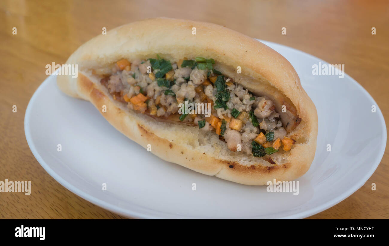 Vietnamese pork Banh Mi sandwich with carrot and spring onion on white dish , selective focus Stock Photo