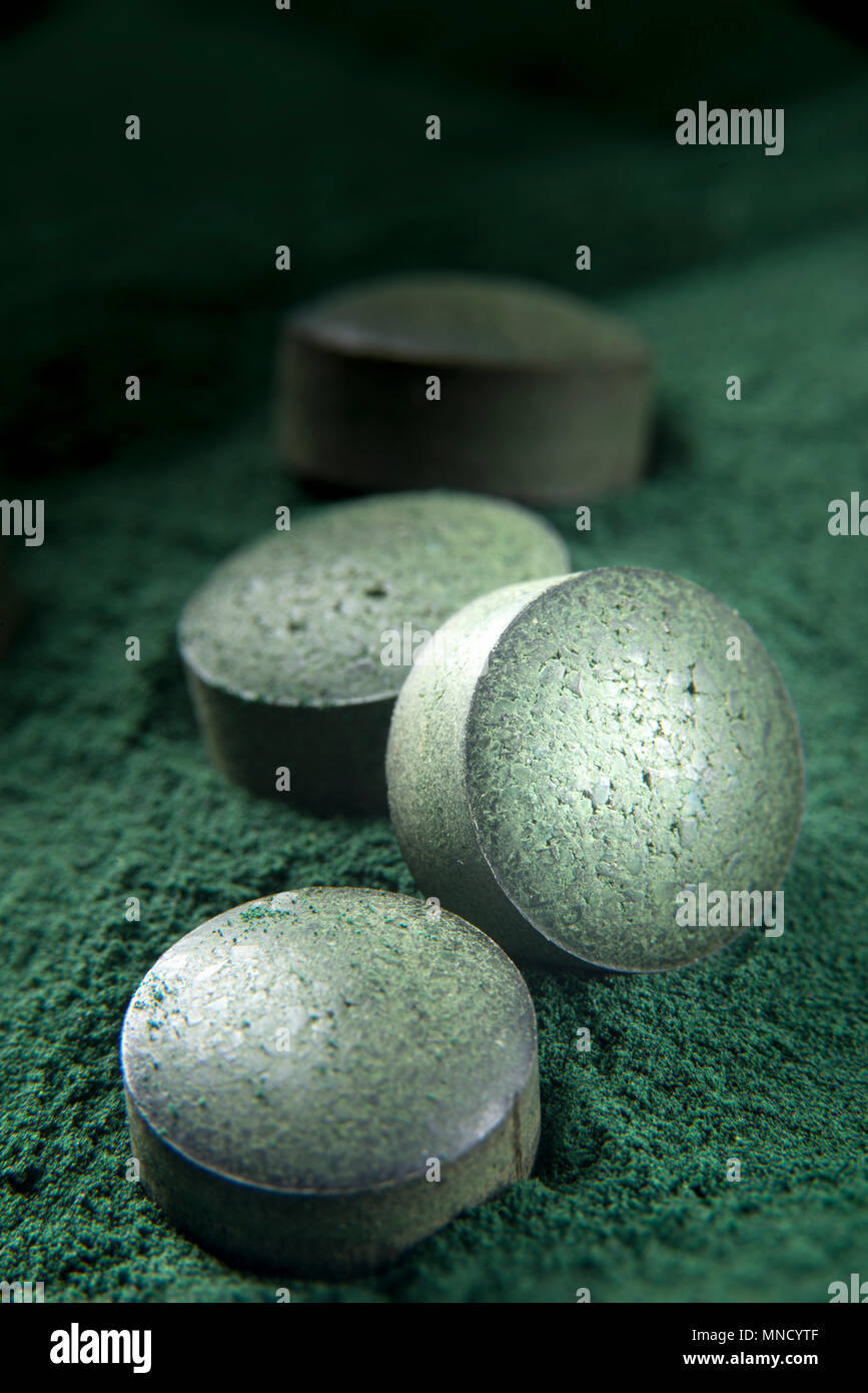 Close up of spirulina tablets on powder background with low depth of field. Vertical image. Stock Photo