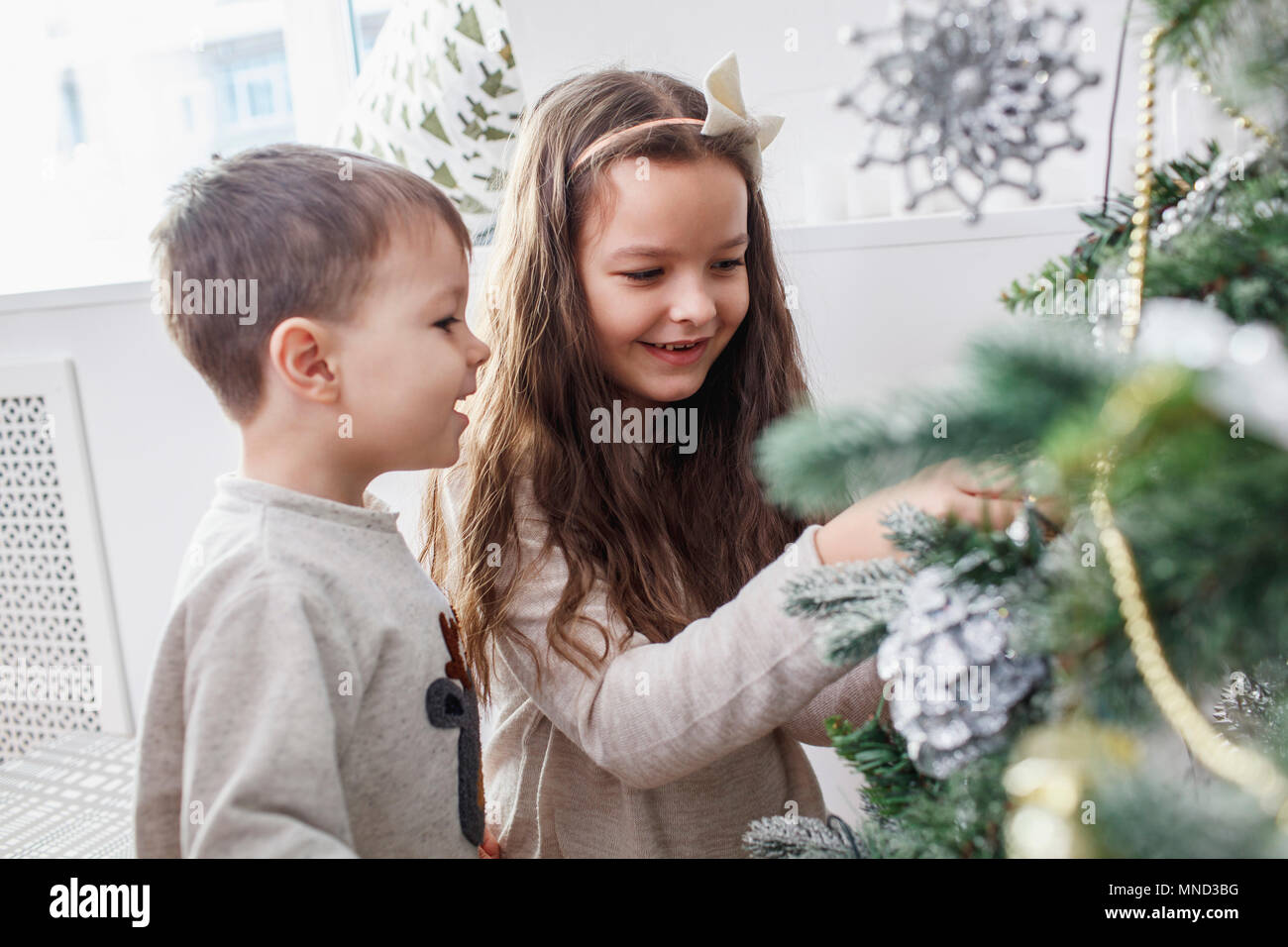 Happy siblings decorating Christmas tree at home Stock Photo