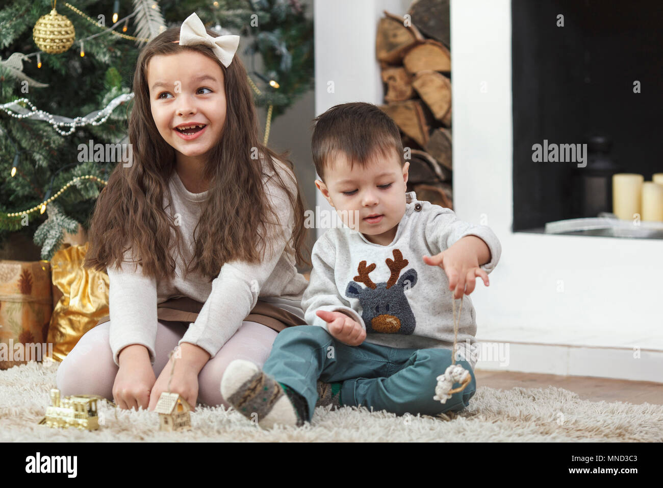 Cheerful girl sitting by brother on rug at home Stock Photo