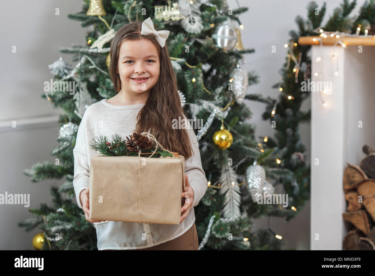 Portrait of smiling girl holding gift against Christmas tree at home Stock Photo