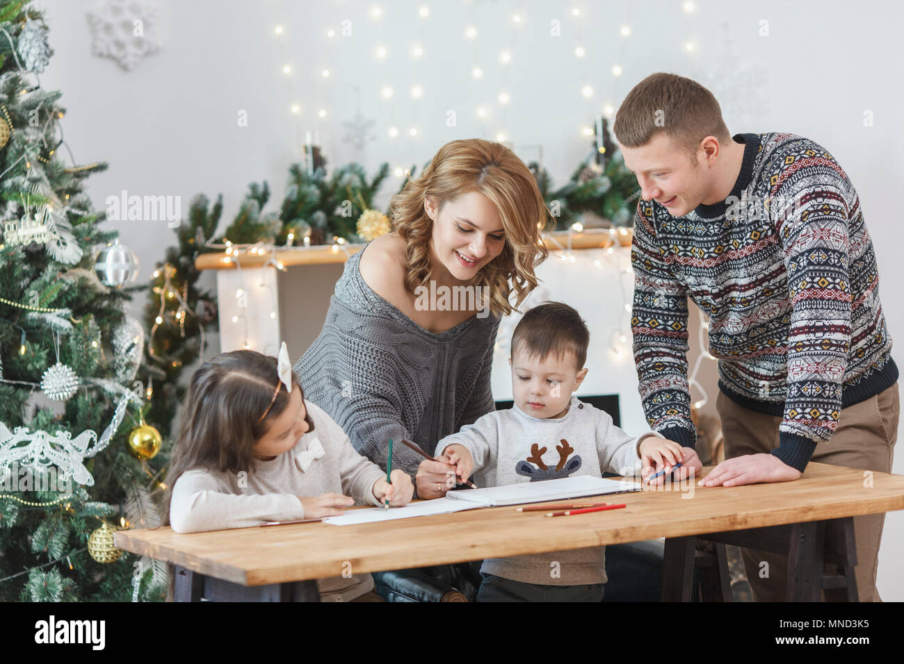 Man looking at woman and children drawing in book on table at home Stock Photo