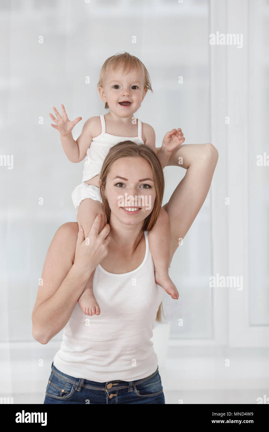 Portrait of happy mother carrying daughter on shoulders at home Stock