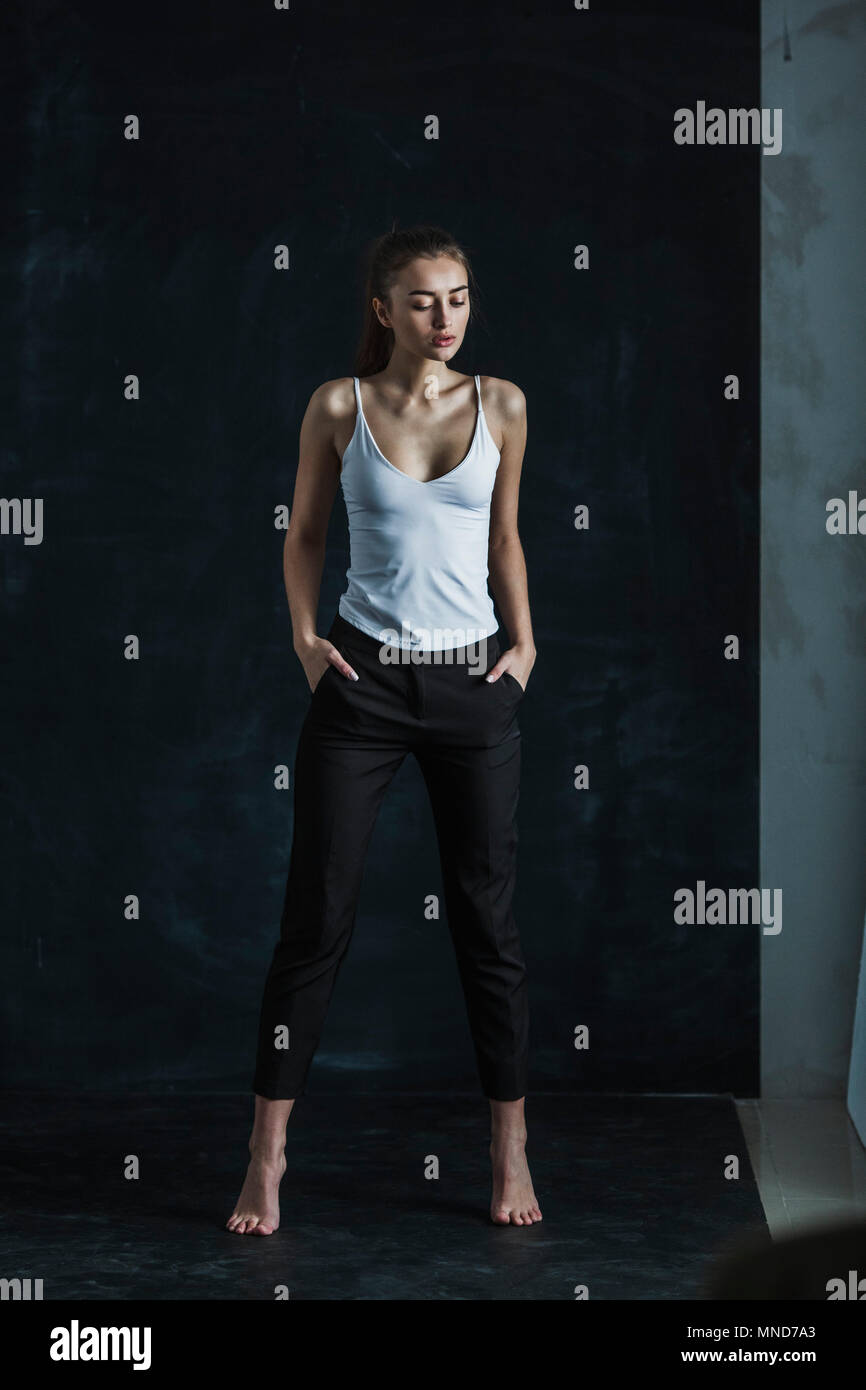 Full length of young fashion model standing against black backdrop Stock Photo
