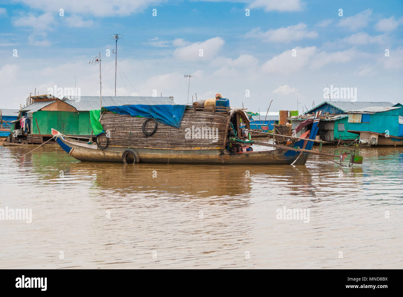 A sampan-like boat, including a small shelter with a curved roof made of wood and thatch that might be a permanent habitation in Chong Kneas. Stock Photo