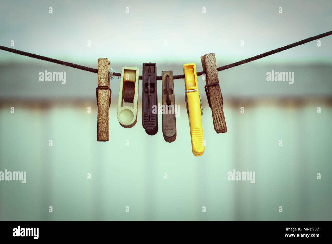 old clothespins on a rope hanging outside house, toned green, vintage look Stock Photo