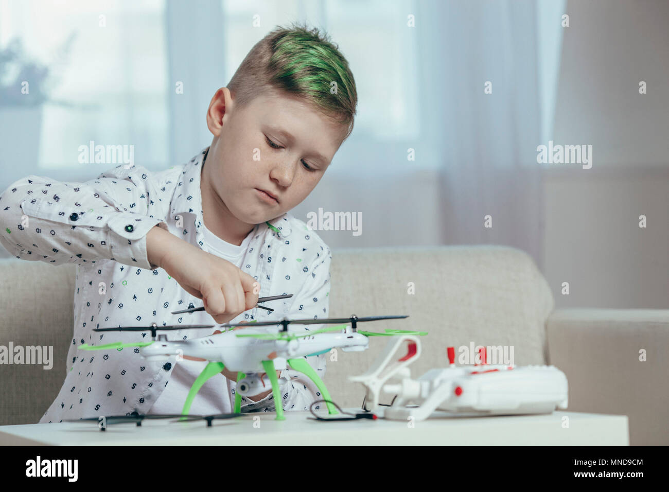 Confident boy adjusting drone on coffee table while sitting at home Stock Photo