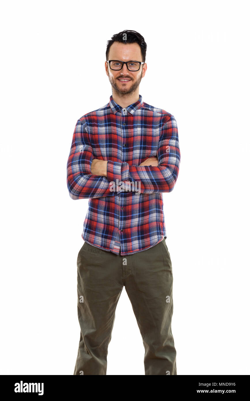 Studio shot of happy young man smiling and standing with arms crossed ...