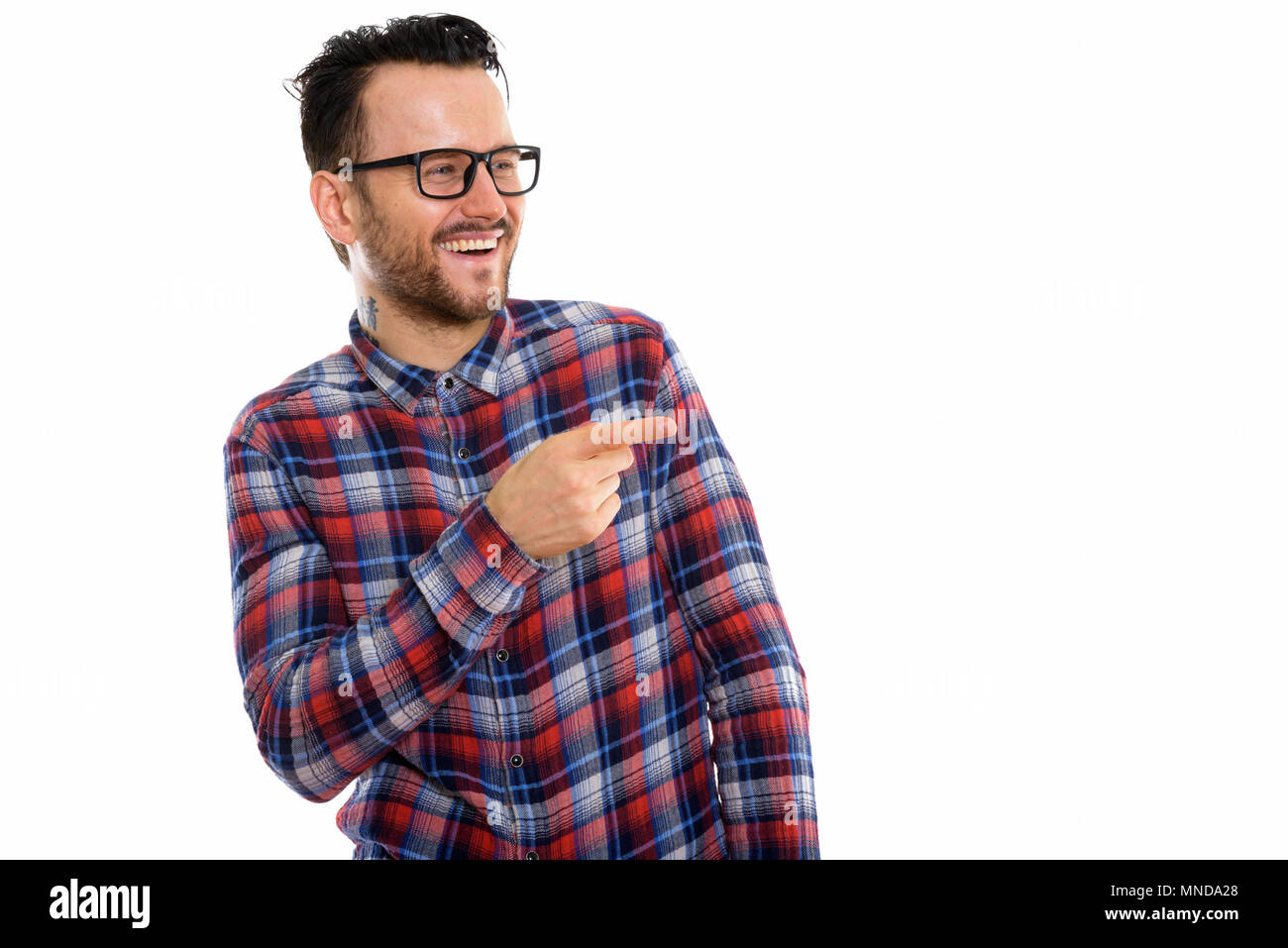 Studio shot of happy young man smiling and laughing while pointing at side Stock Photo