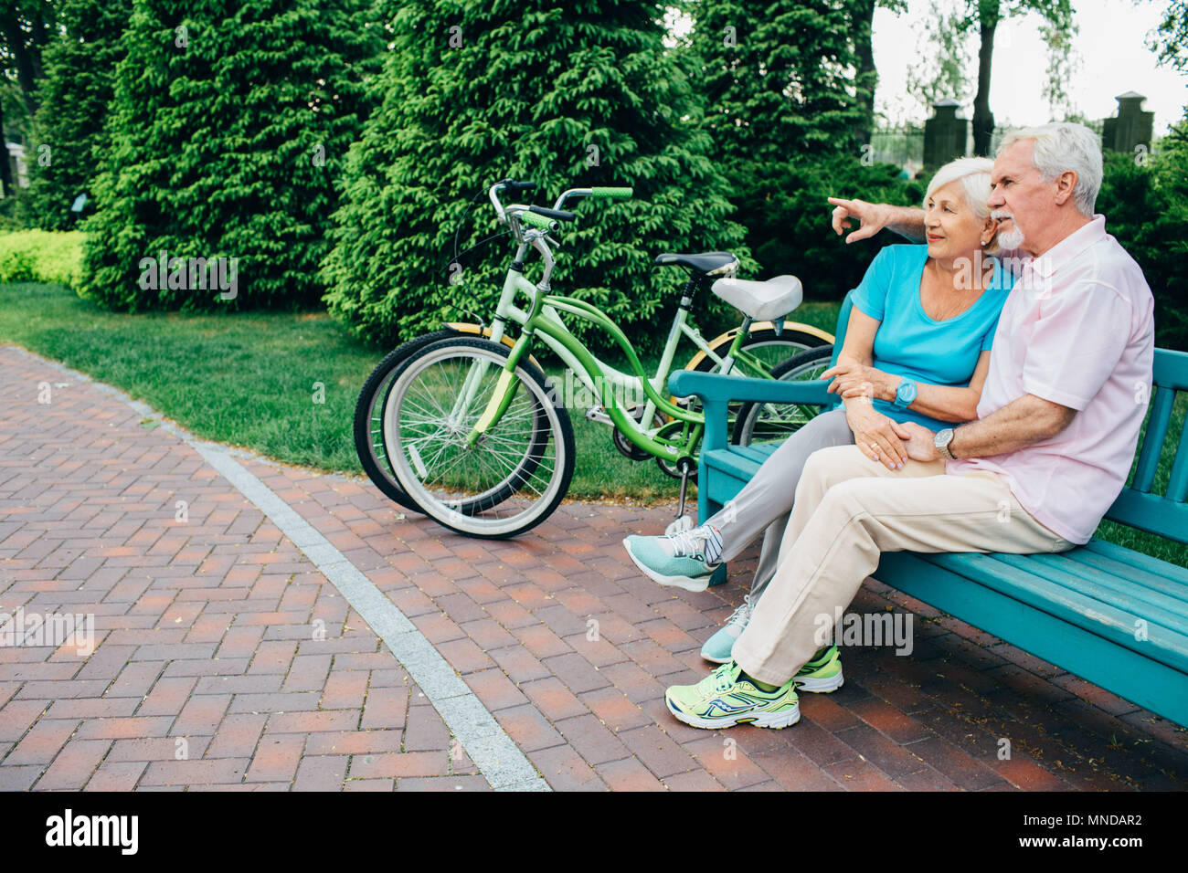 elderly active couple sitting in a city park Stock Photo