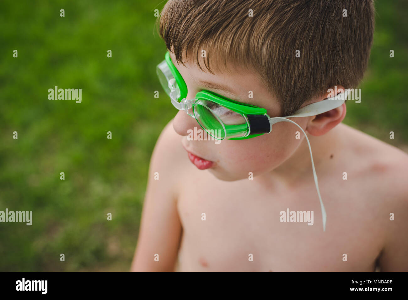 A boy wearing green swimming goggles on a sunny summer day Stock Photo