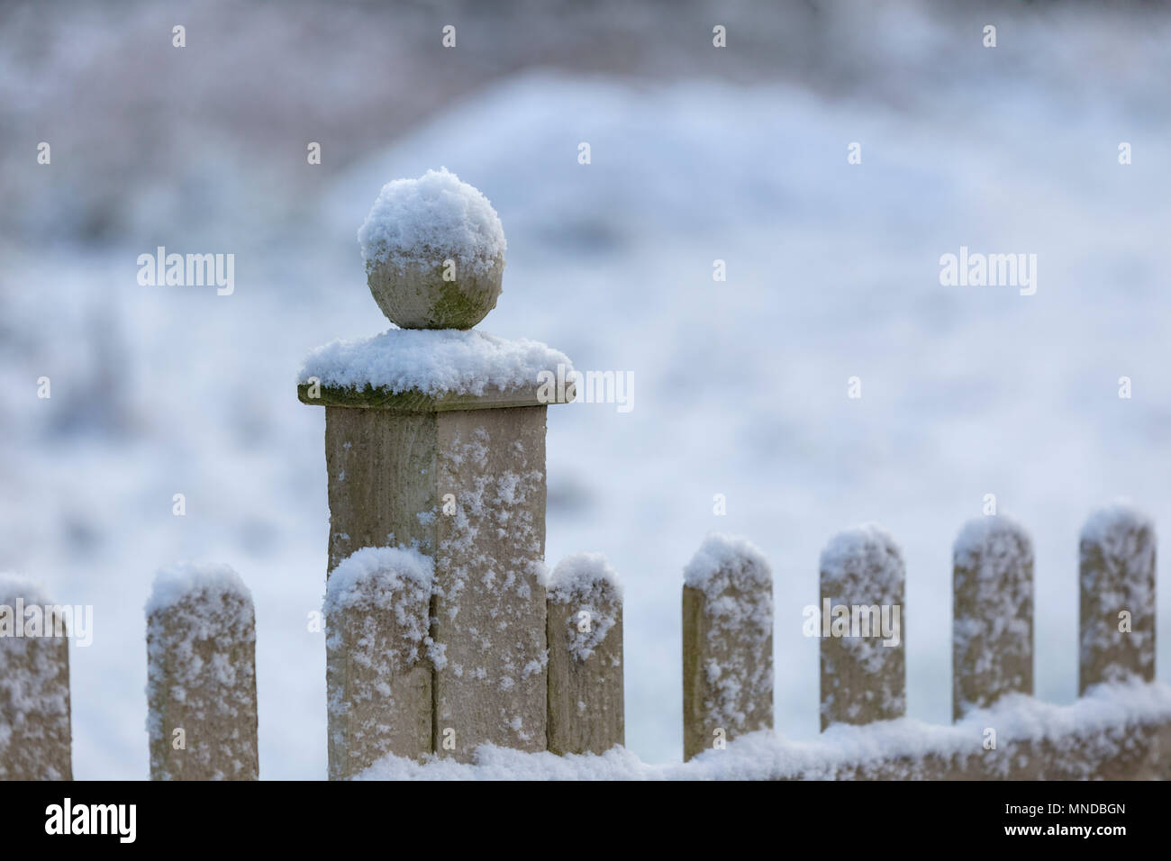 Snow capped wooden fence with a ball finial. Stock Photo