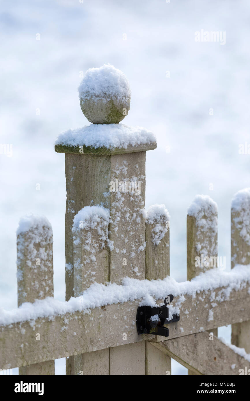 Snow capped wooden fence with a ball finial. Stock Photo